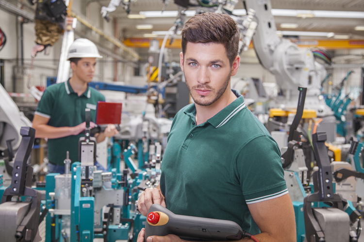 Image of mechanical workers working with one man looking straight into the camera